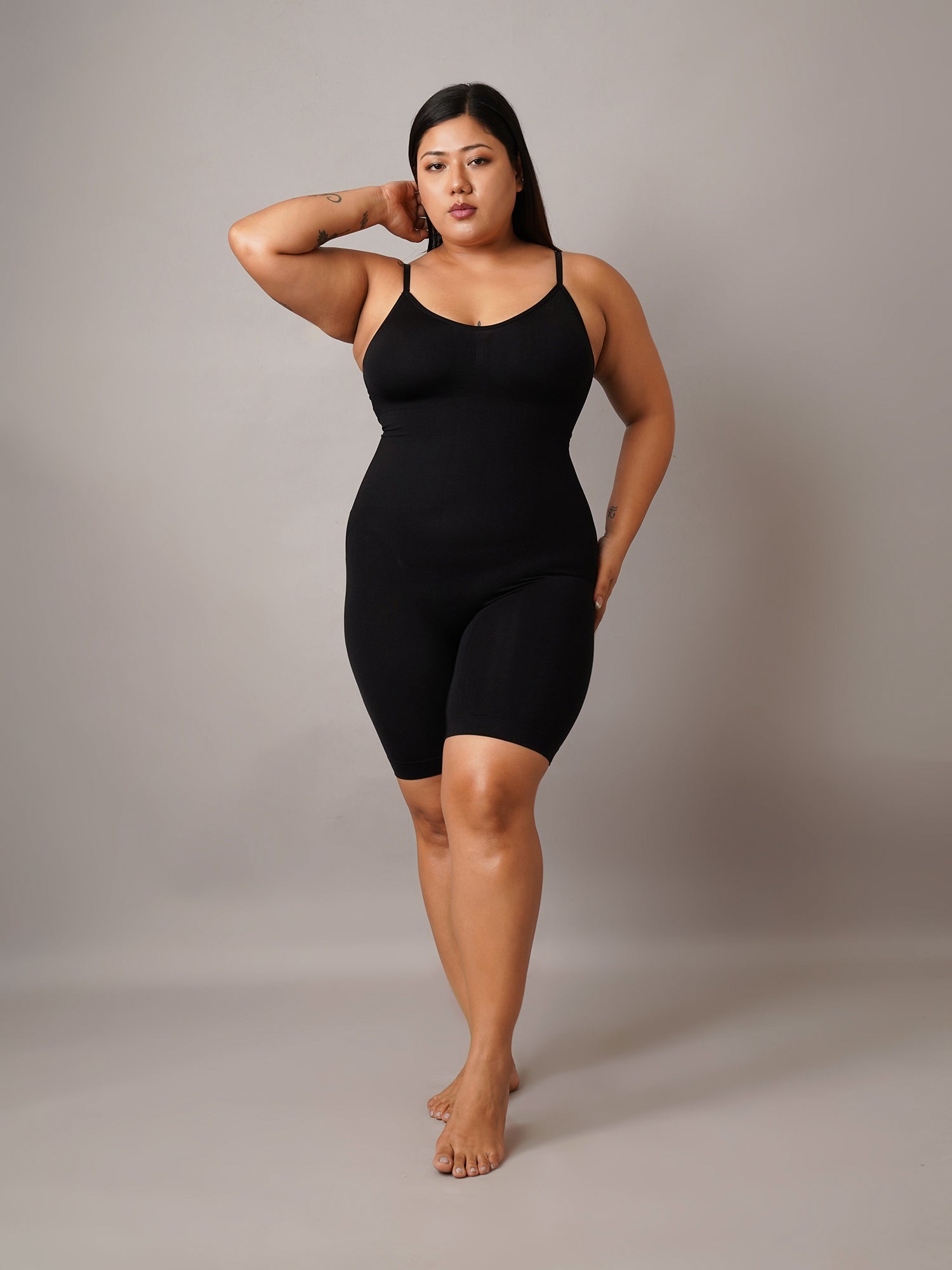 Women wearing a black bodysuit against a plain background